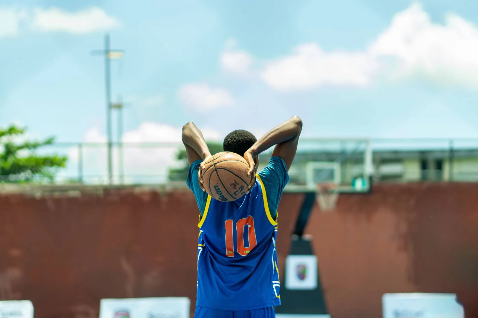 Young basketball player holding the ball overhead on the court